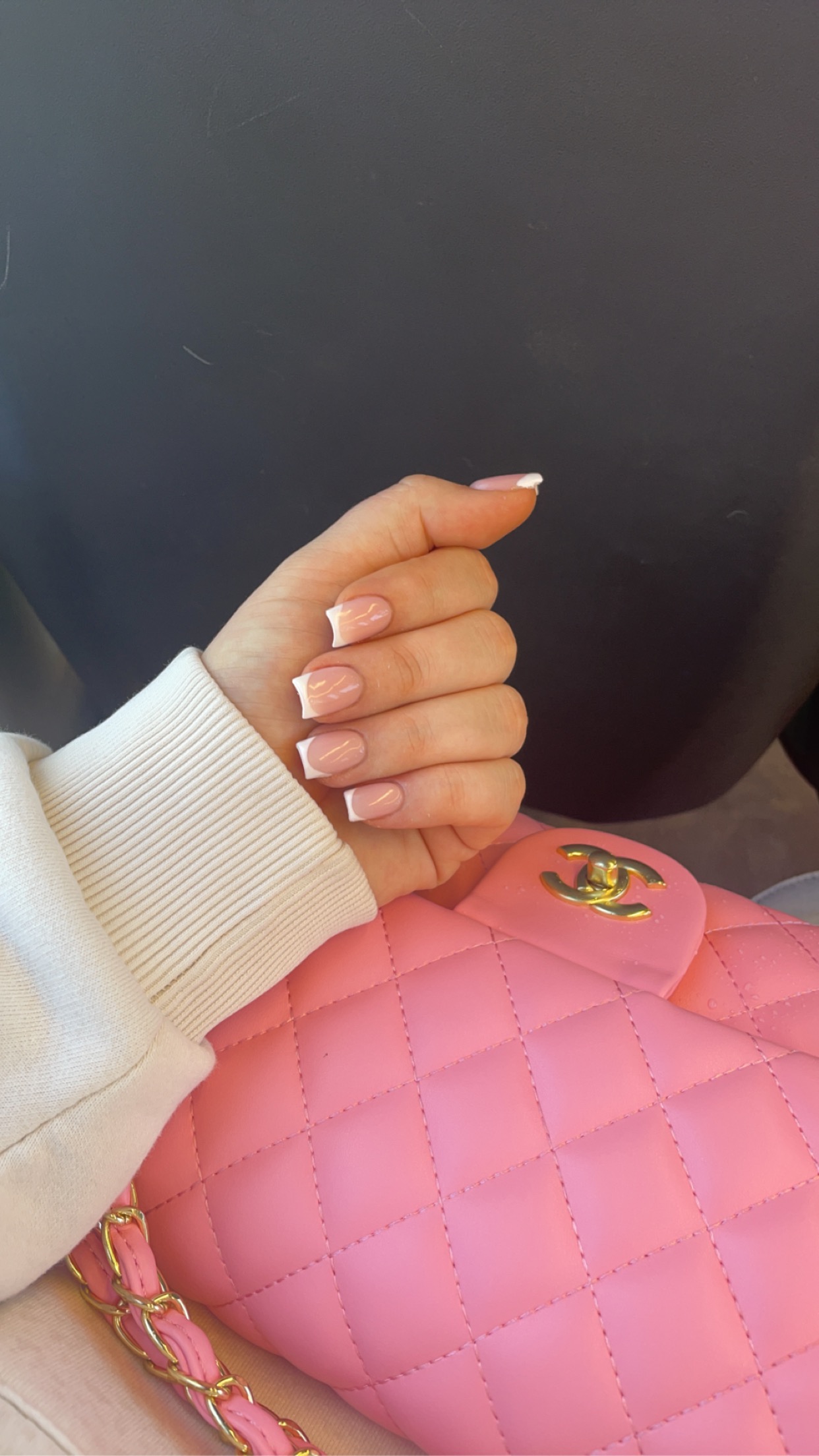 Korte french nagels bij een roze tas